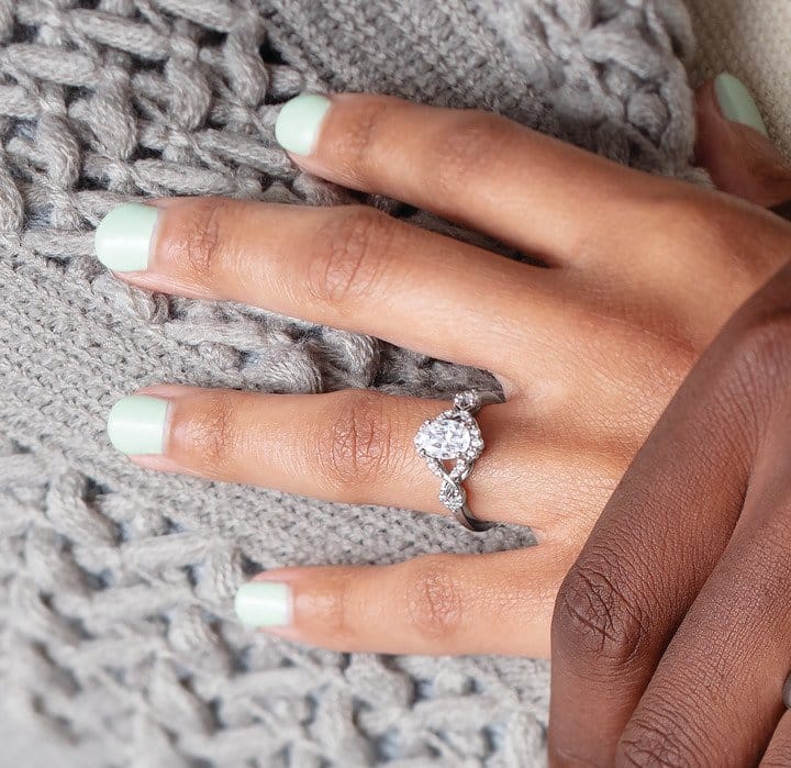 Hand with an engagement ring on a cozy knitted fabric.