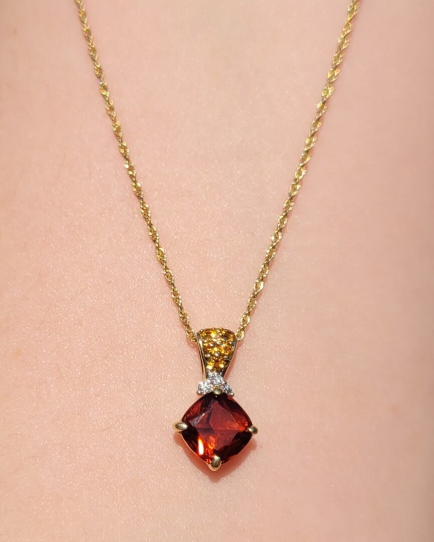 Elegant gold necklace with a deep red gemstone pendant.