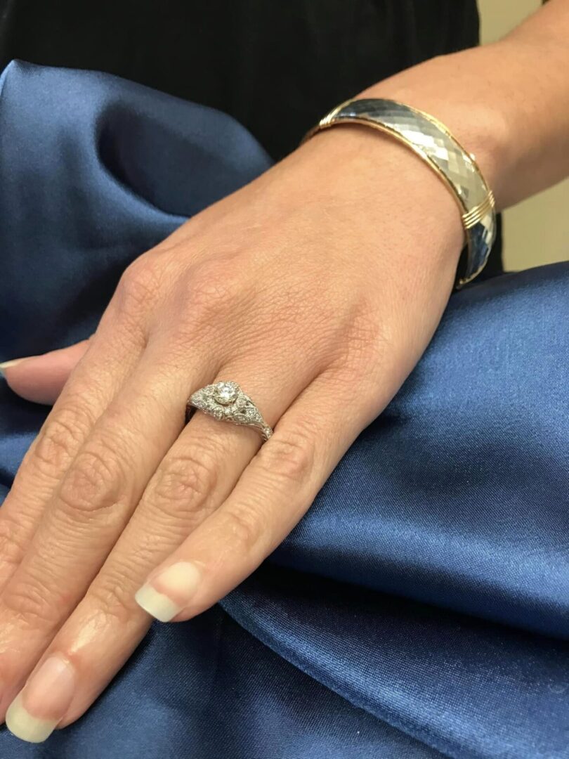Close-up of a hand wearing a silver ring and bracelet on blue fabric.
